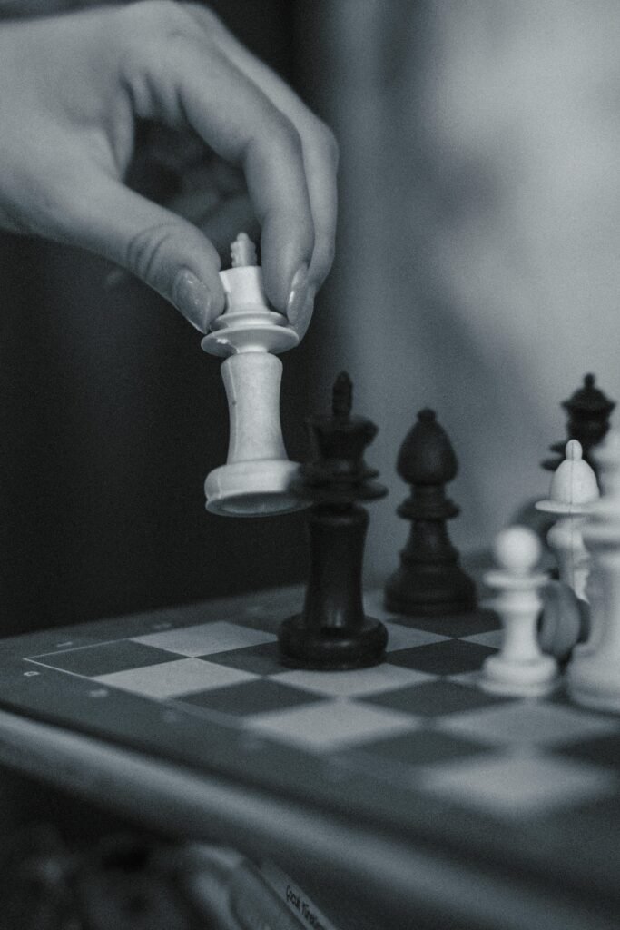 A close-up of a strategic chess move with a human hand on a wooden chessboard.