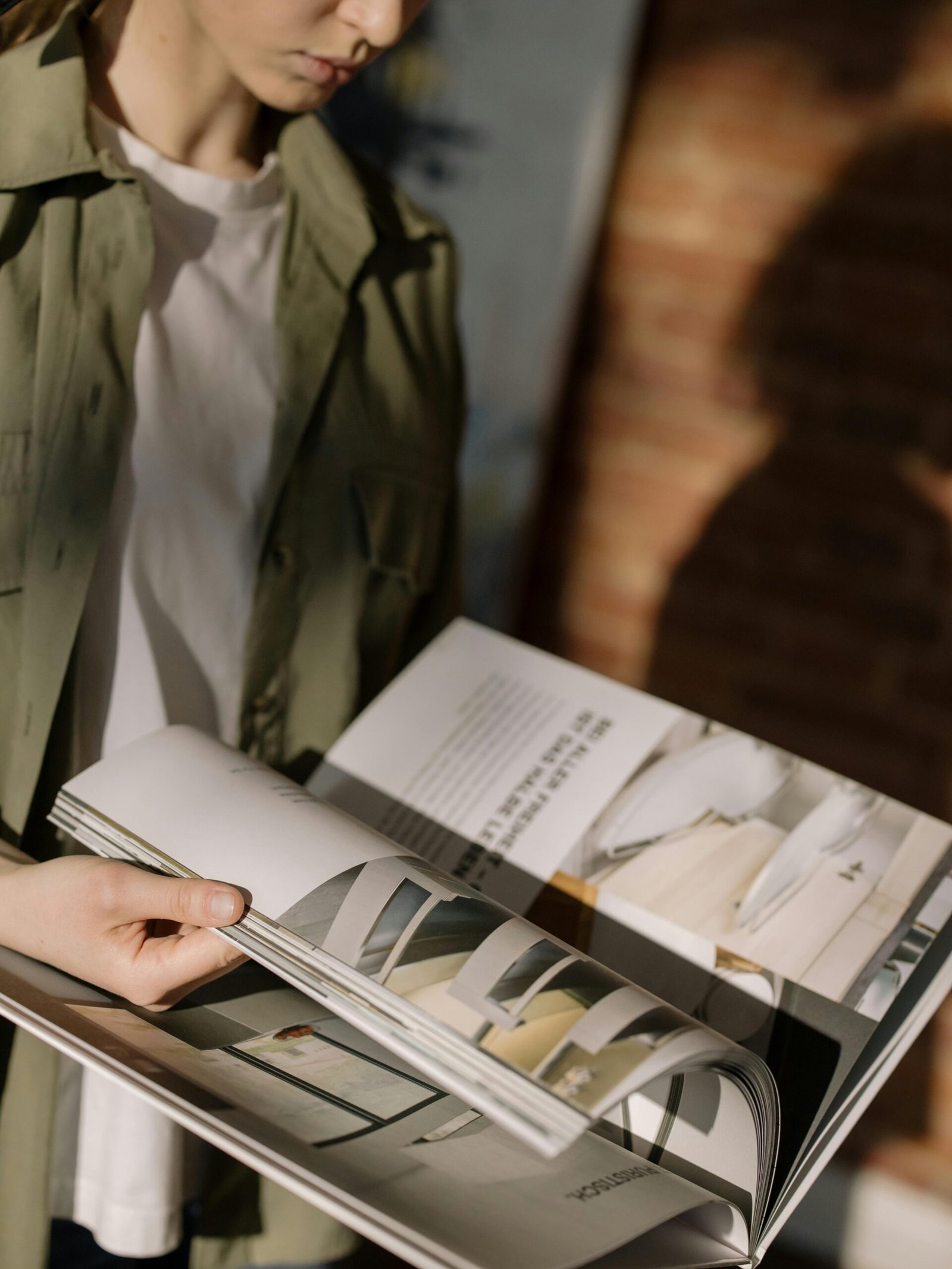 Close-up of a person browsing through a design magazine indoors.