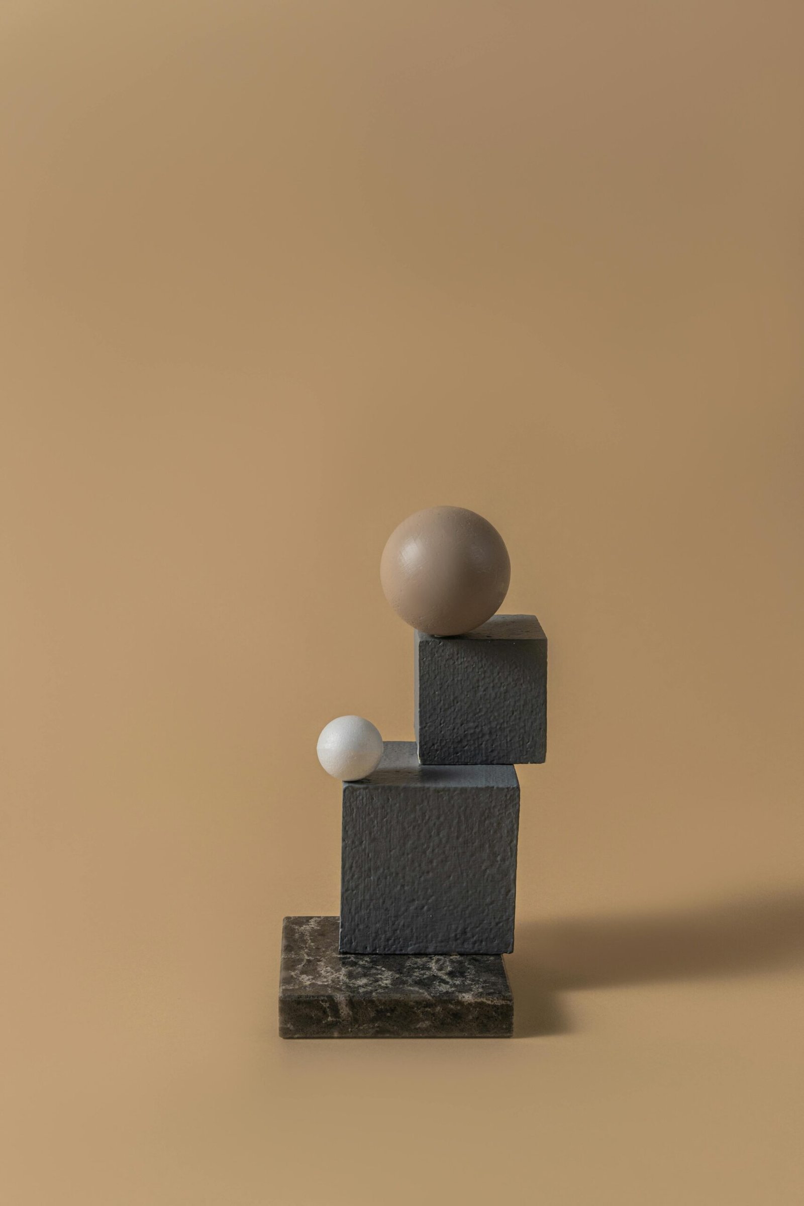 Artistic arrangement of spheres and cubes on a textured surface, showcasing minimalism and balance.